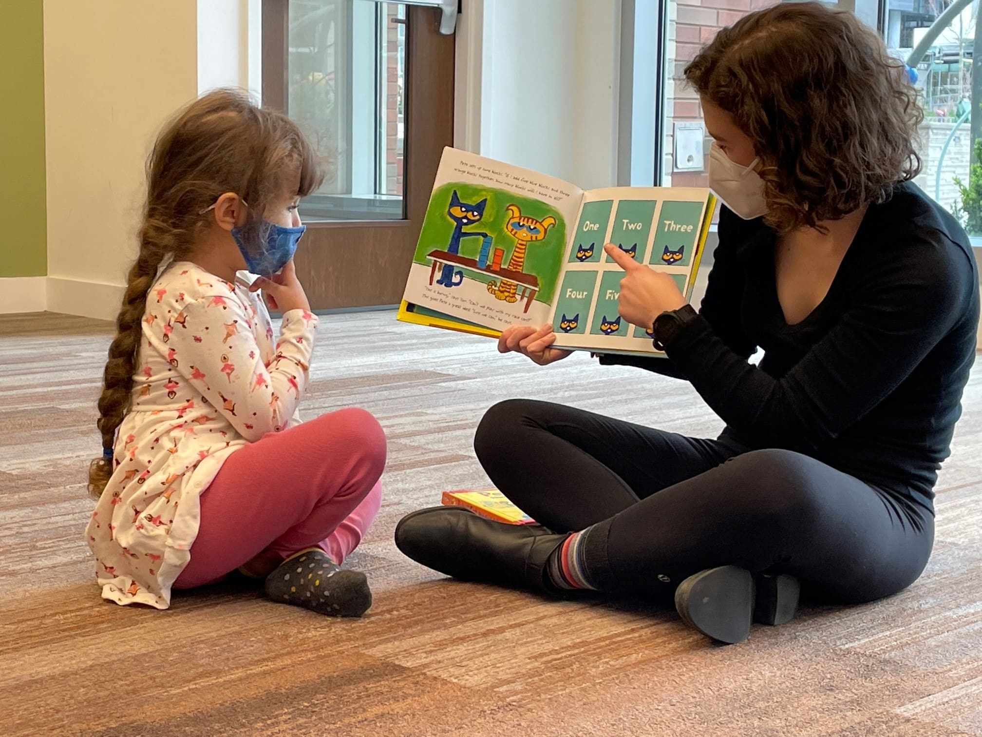 Teacher next to her student, pointing to a page in a book