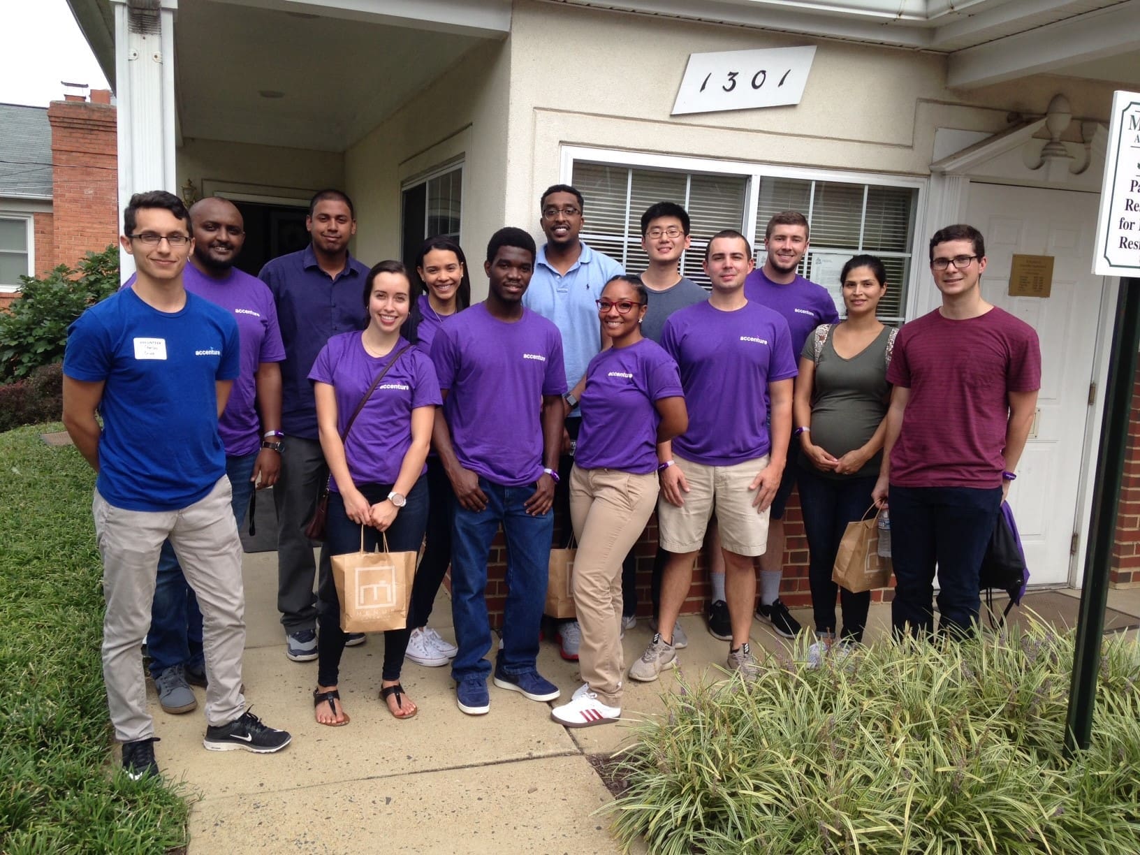 Group of volunteers in purple and blue shirts standing outside a building.