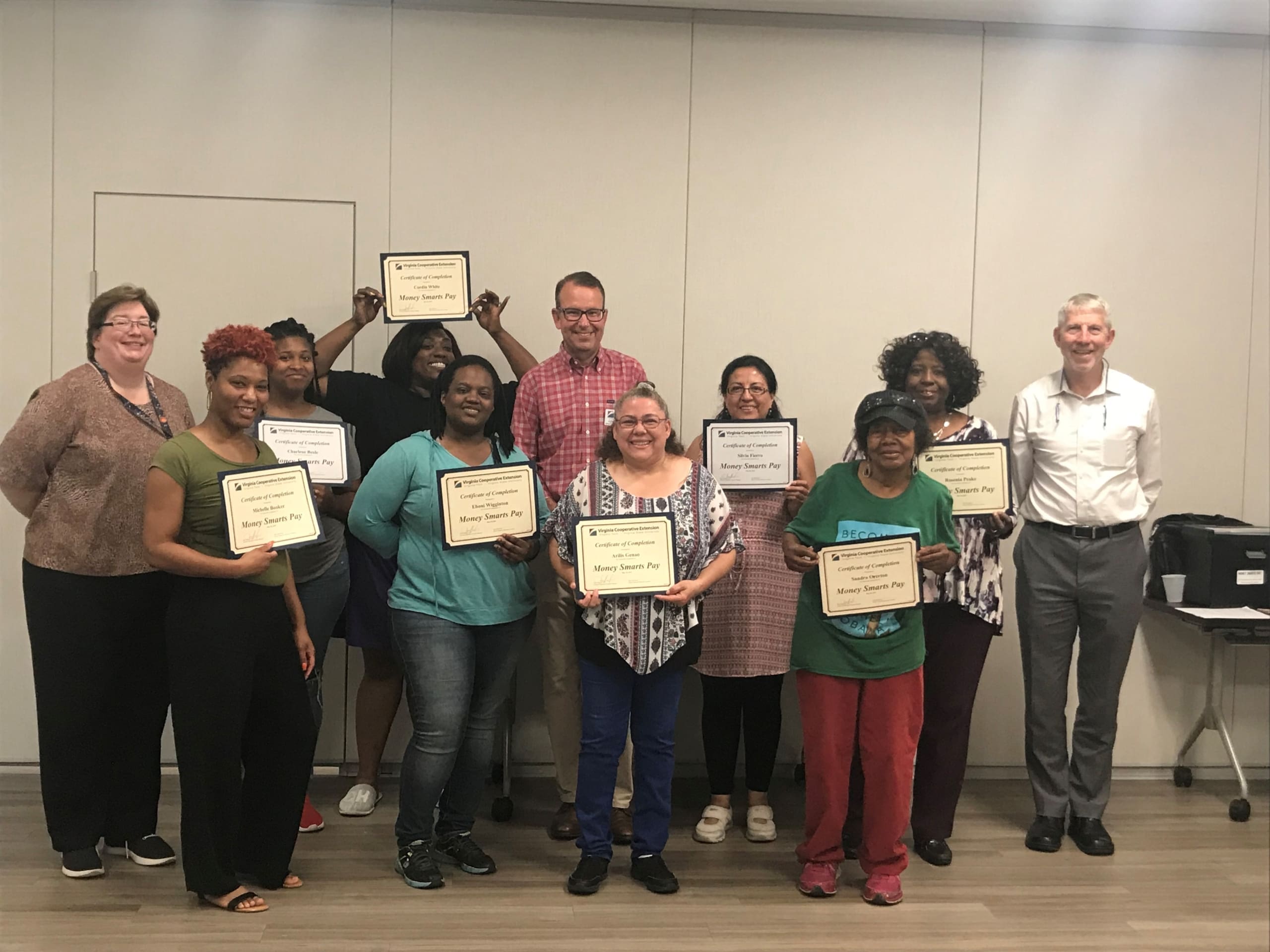 Group of individuals proudly holding certificates of completion.