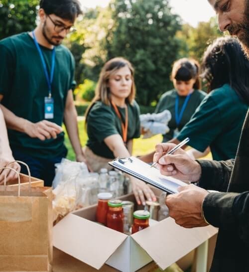 Group of volunteers in green shirts organizing and inventorying donation items.
