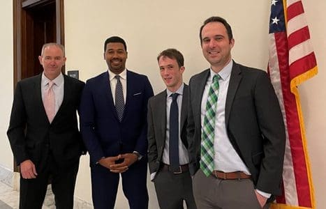 Four men smiling for the photo, wearing suits and ties