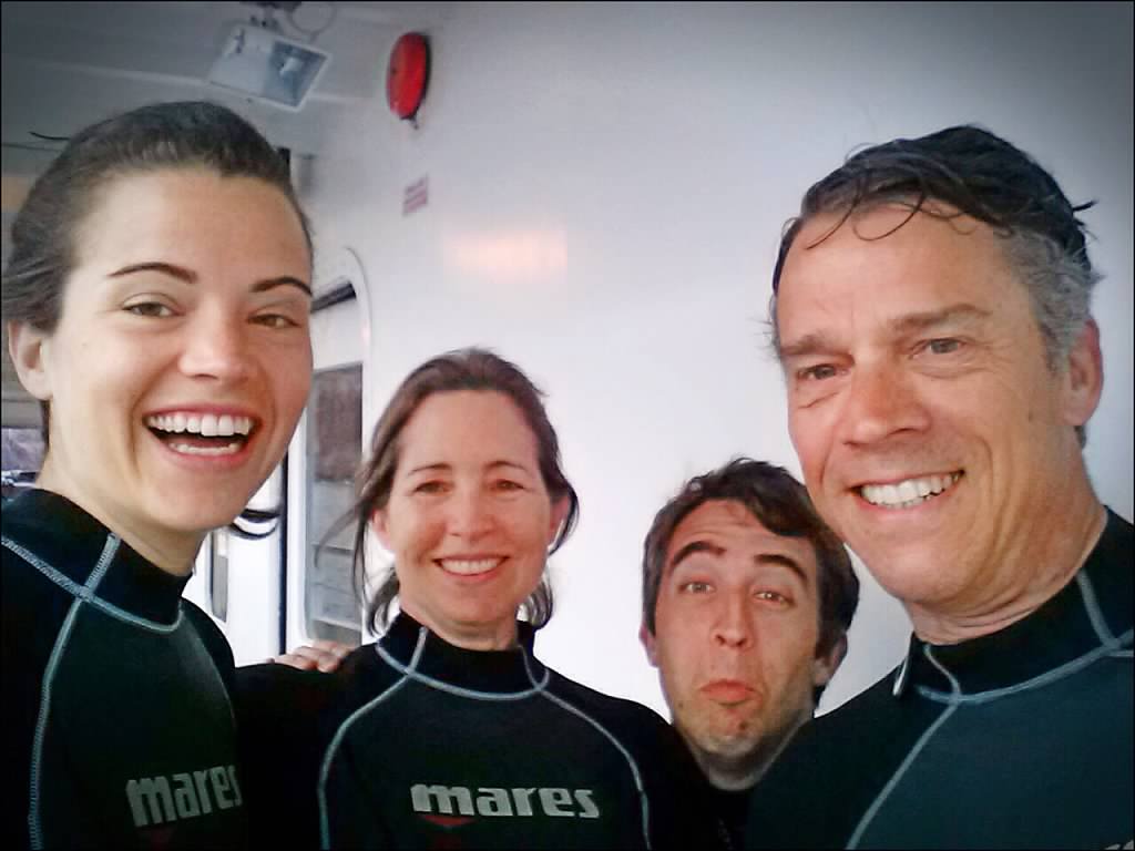 Smiling group in scuba gear preparing for a dive