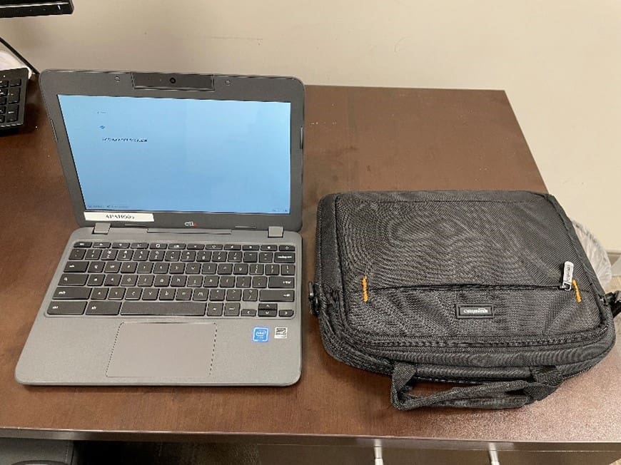 Laptop on a desk, next to a backpack for laptops