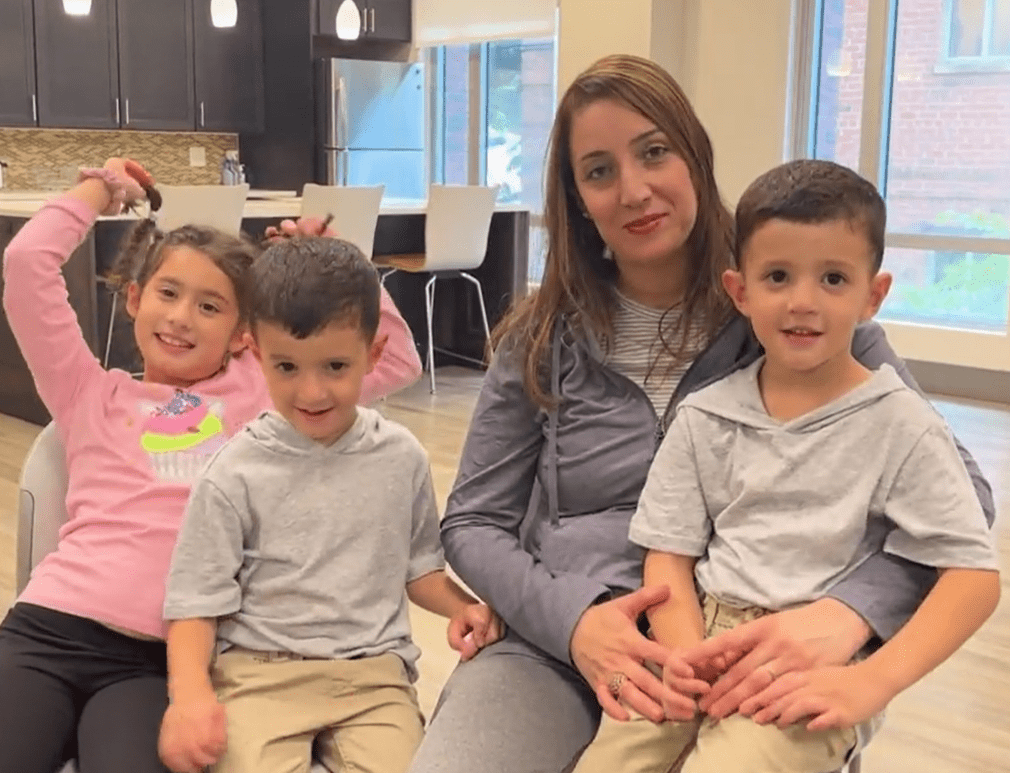 Samia-with-children-3 Woman sitting smiling, with three children, one of them on her lap.