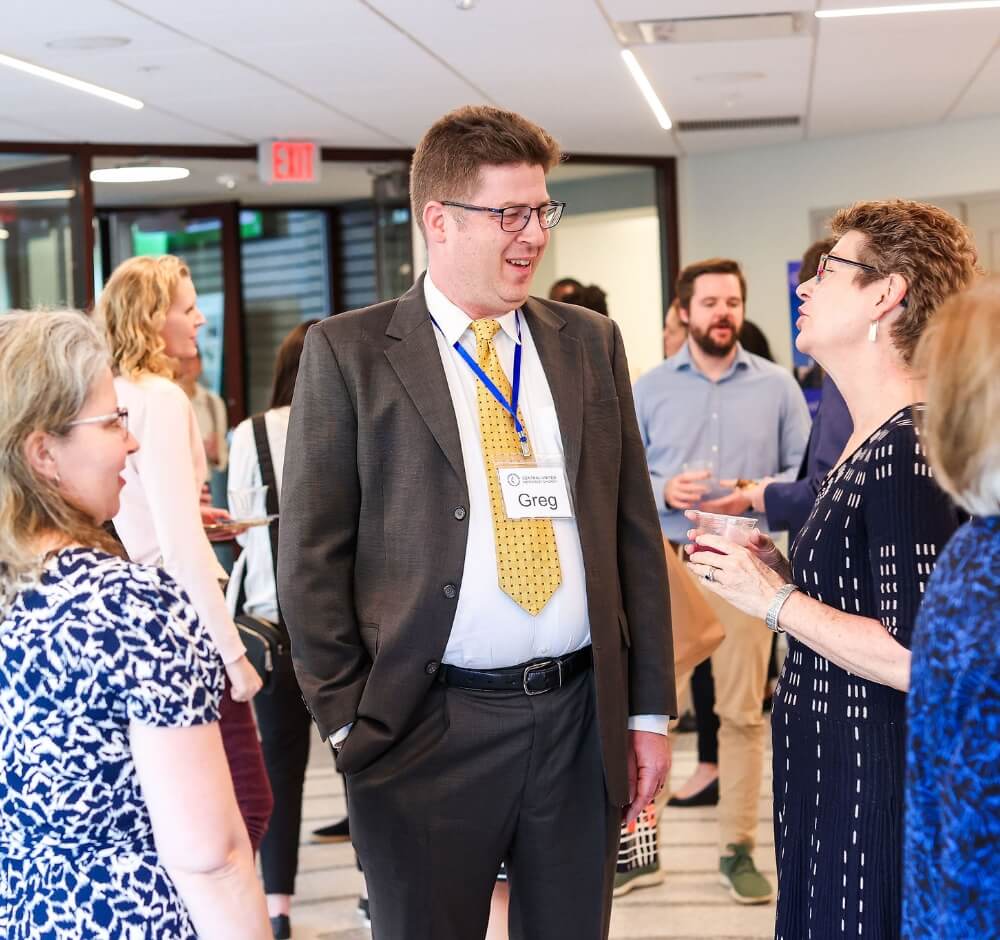True-Ground-Gifts-Donor-FAQs@2x People networking and conversing at a professional event