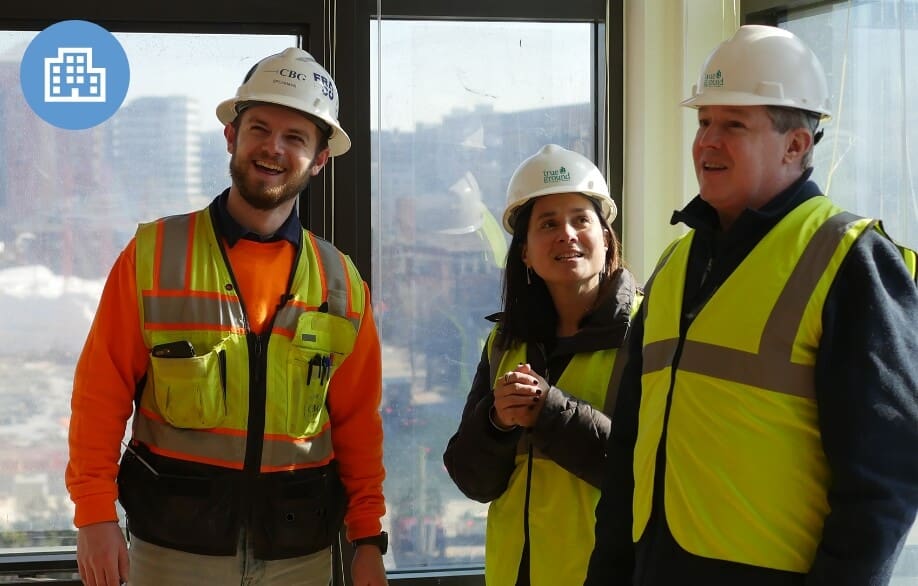 Construction workers and a project manager in safety vests and hard hats on-site