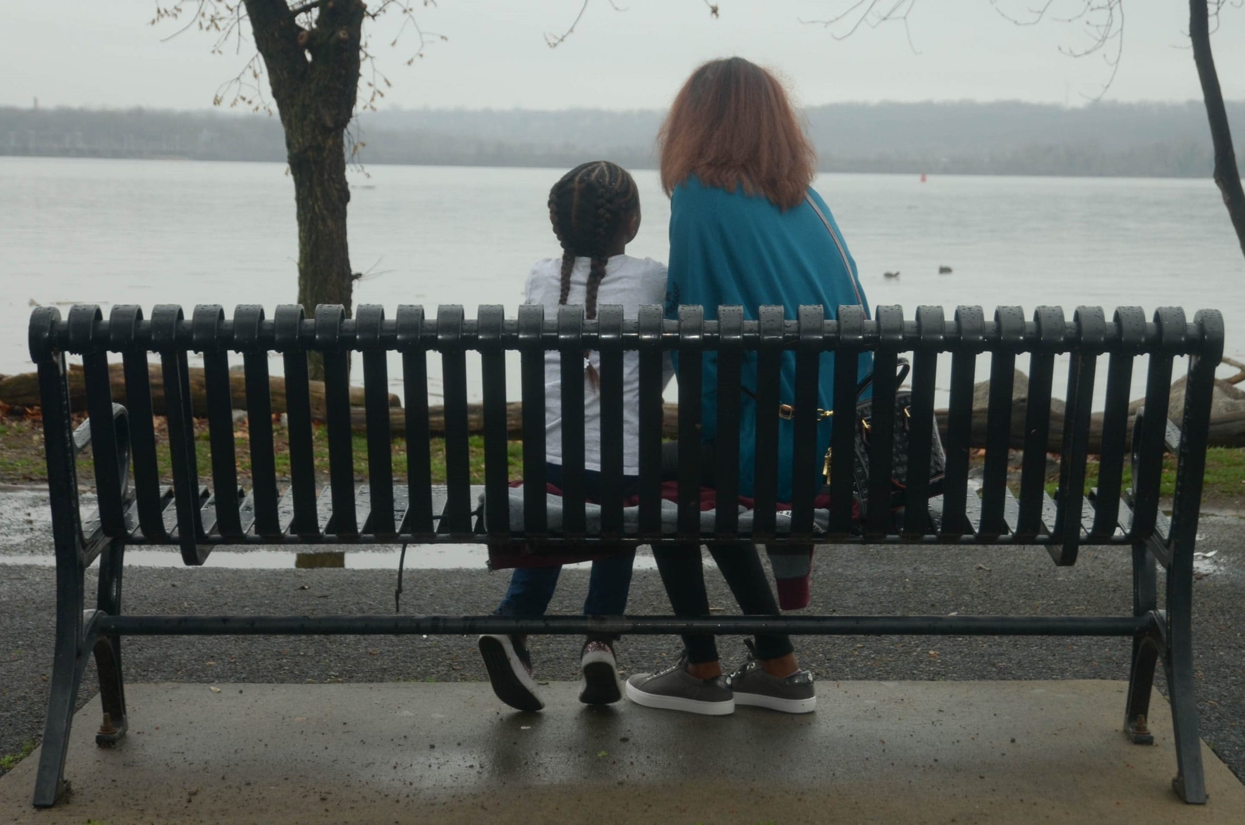 Mother and daughter sitting on a bench, in front of the sea